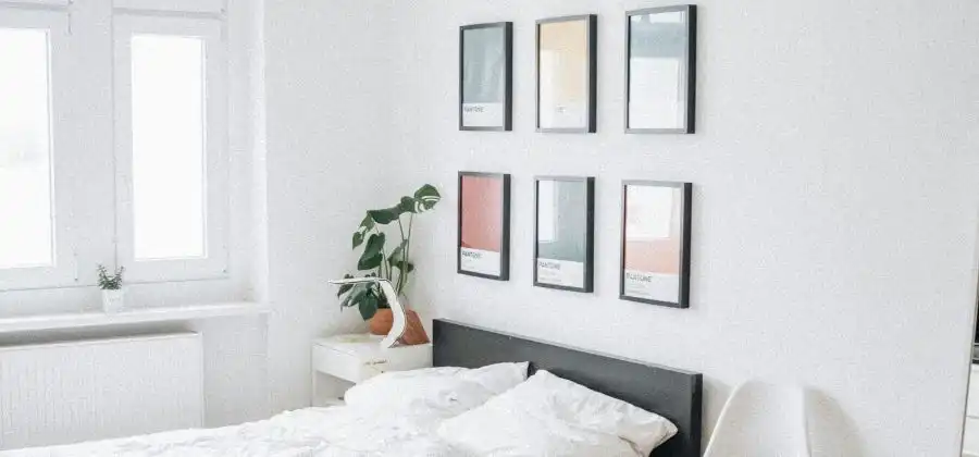 Quarto com cama e quadros pendurados na parede simbolizando habitação para jovens