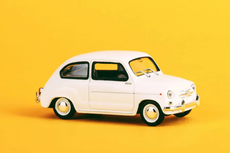 Carro clássico branco em fundo amarelo - representação visual do tema automóvel relacionado com impostos como o IUC.