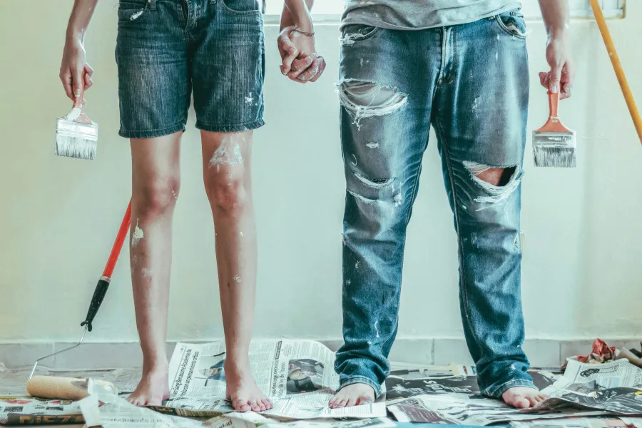 Interior de uma casa em remodelação com folhas de jornal no chão e casal sujo de tinta