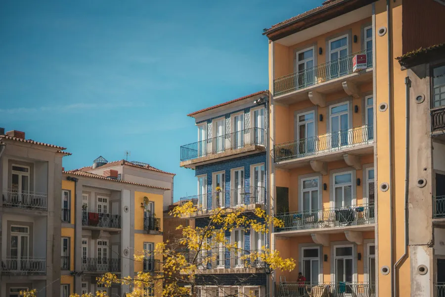 Casa e símbolo de percentagem sobre moedas, representando o impacto do spread nas taxas de juro do crédito habitação.