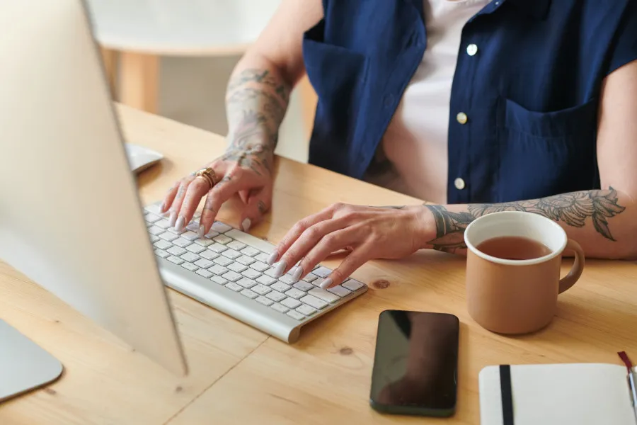 Mulher com as mãos pousadas em cima de um teclado de computador.