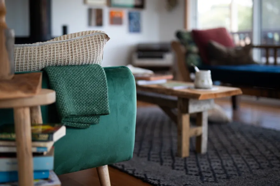 Sala com mesa ao centro e sofá verde, no canto esquerdo. 