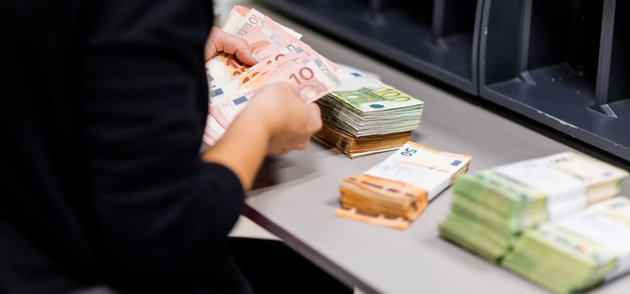 Mulher a organizar montes de notas de 50 e 100 euros simbolizando amortização do crédito habitação