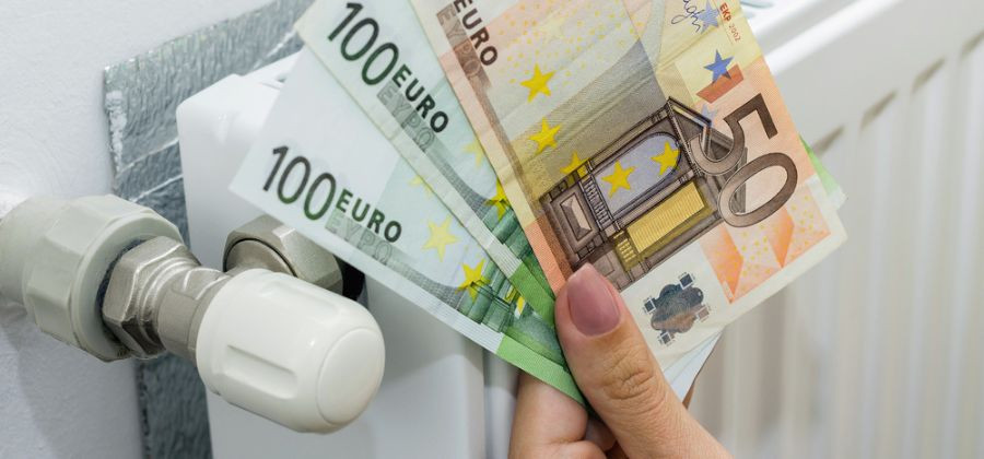 Aquecedor a gás e mulher com mão à frente a exibir notas de 50 e 100 euros 
