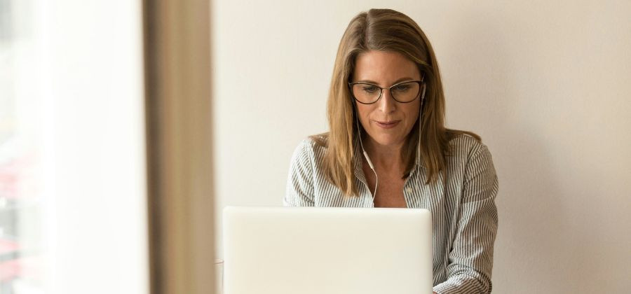 Mulher de óculos em frente de computador com fones a atentar a fraude