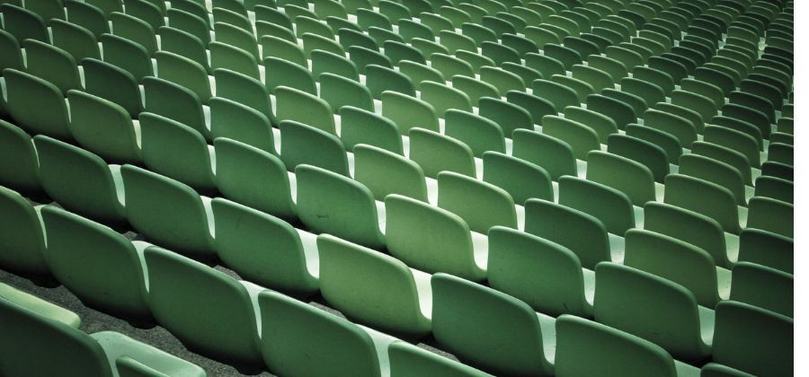 Cadeiras verdes em sala de espetáculo simbolizando revender bilhetes