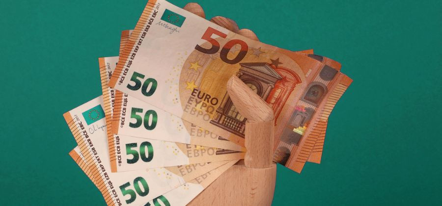 Mão de madeira a segurar notas de 50 euros para simbolizar inflação