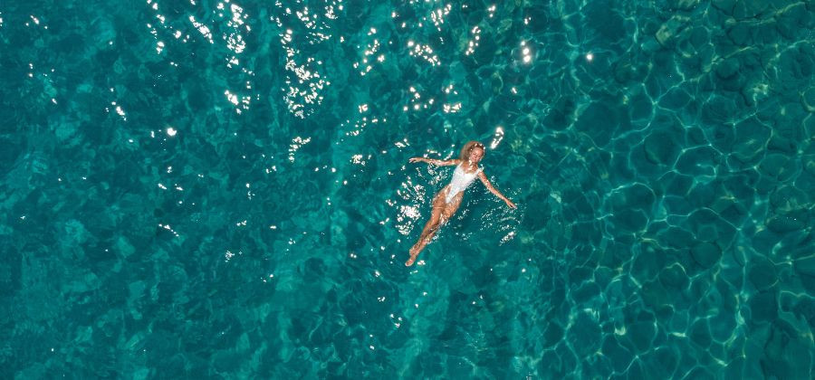 Mulher a boiar sob mar azul simbolizando férias